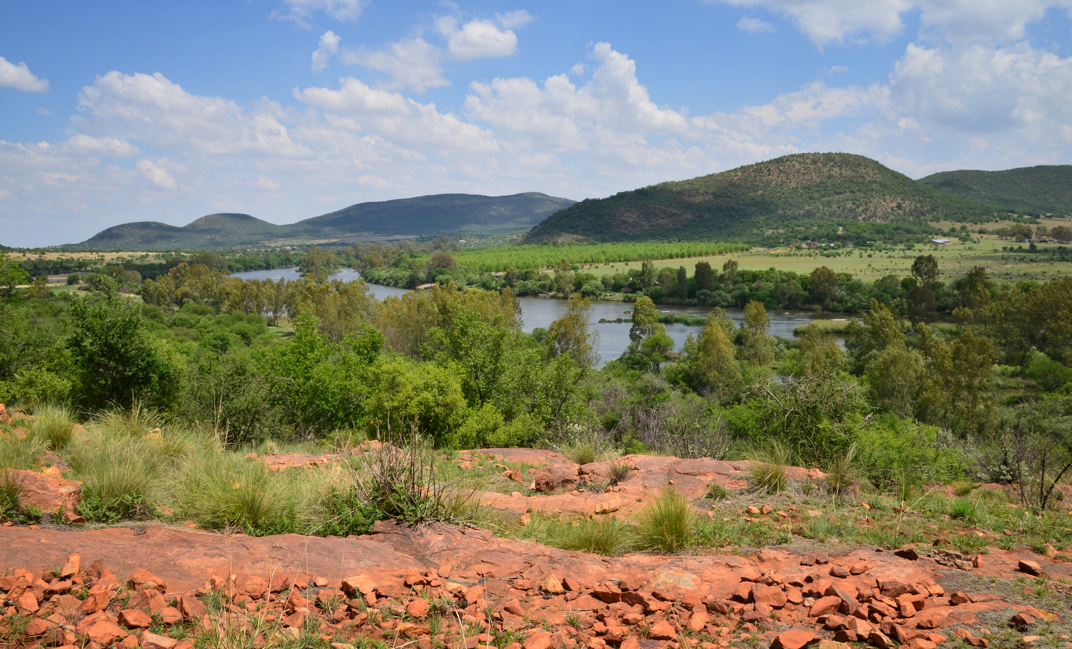 The Vaal River winds between green banks beneath the ridges of the Vredefort Dome.